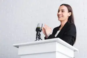 Speaker clapping hands enthusiastically while standing on stage